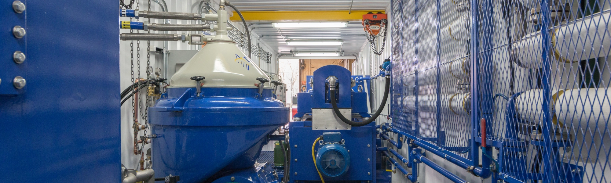 Interior view of a containerized Alfa Laval centrifuge system with piping, safety guarding, and installed industrial centrifuge equipment